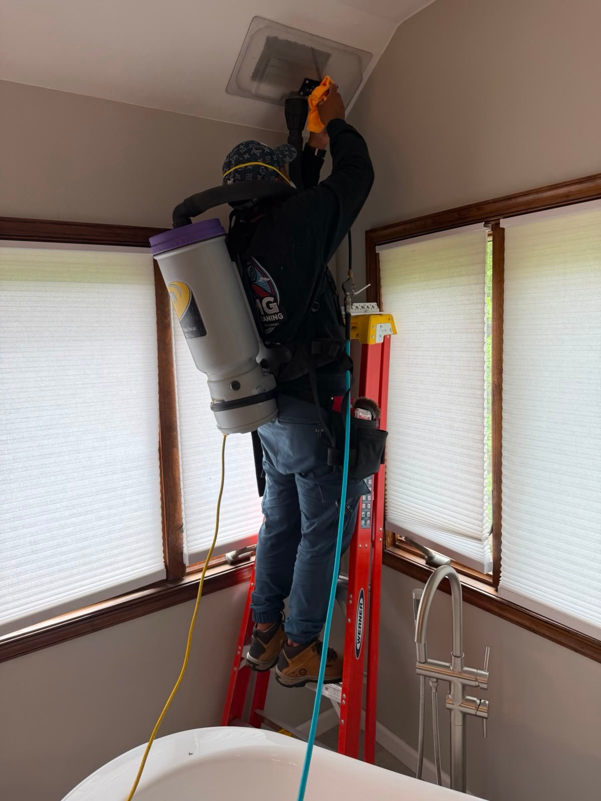 AMG technician using cleaning equipment at a ceiling vent
