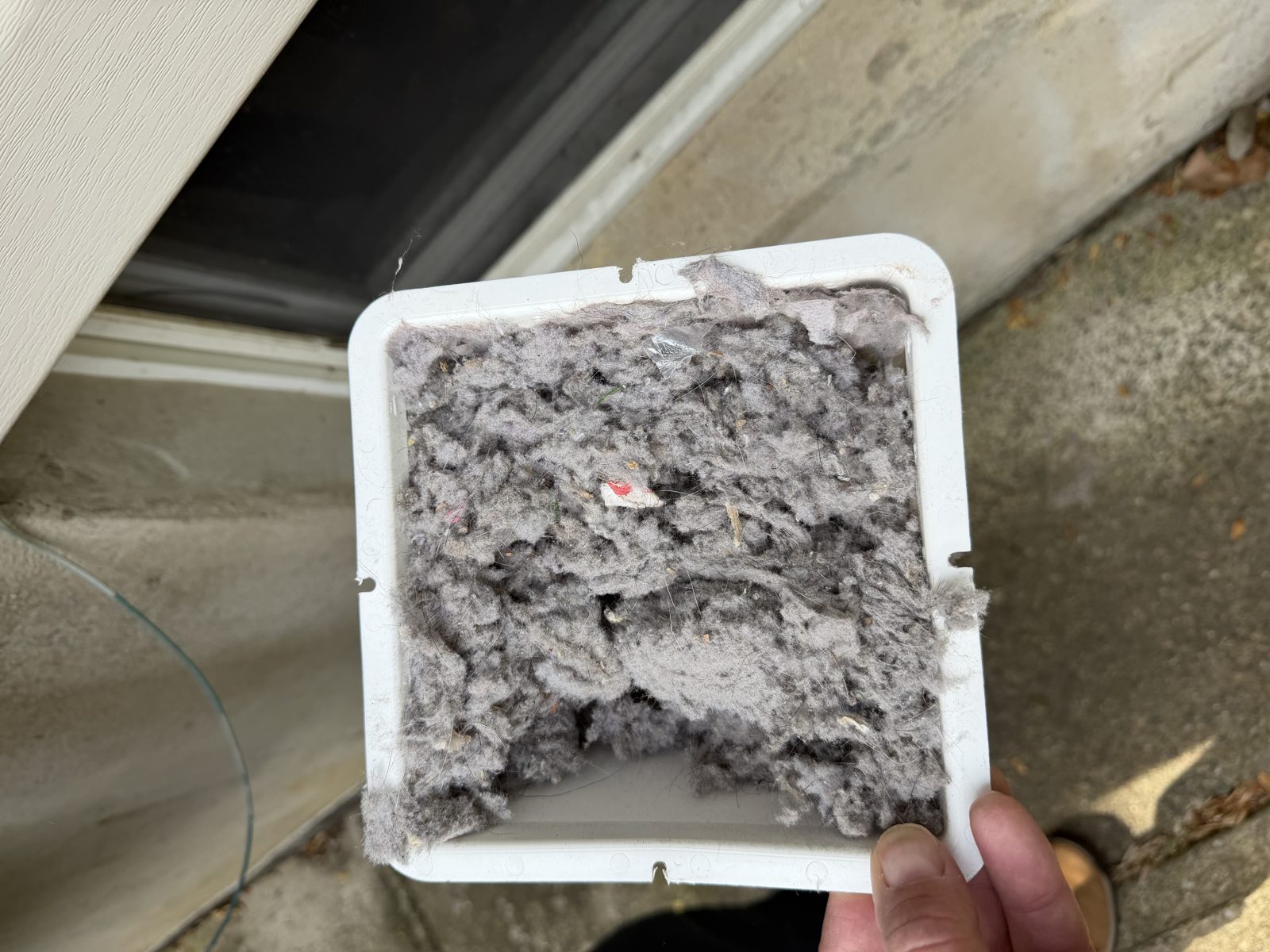 A vent cover full of lint held by an AMG technician