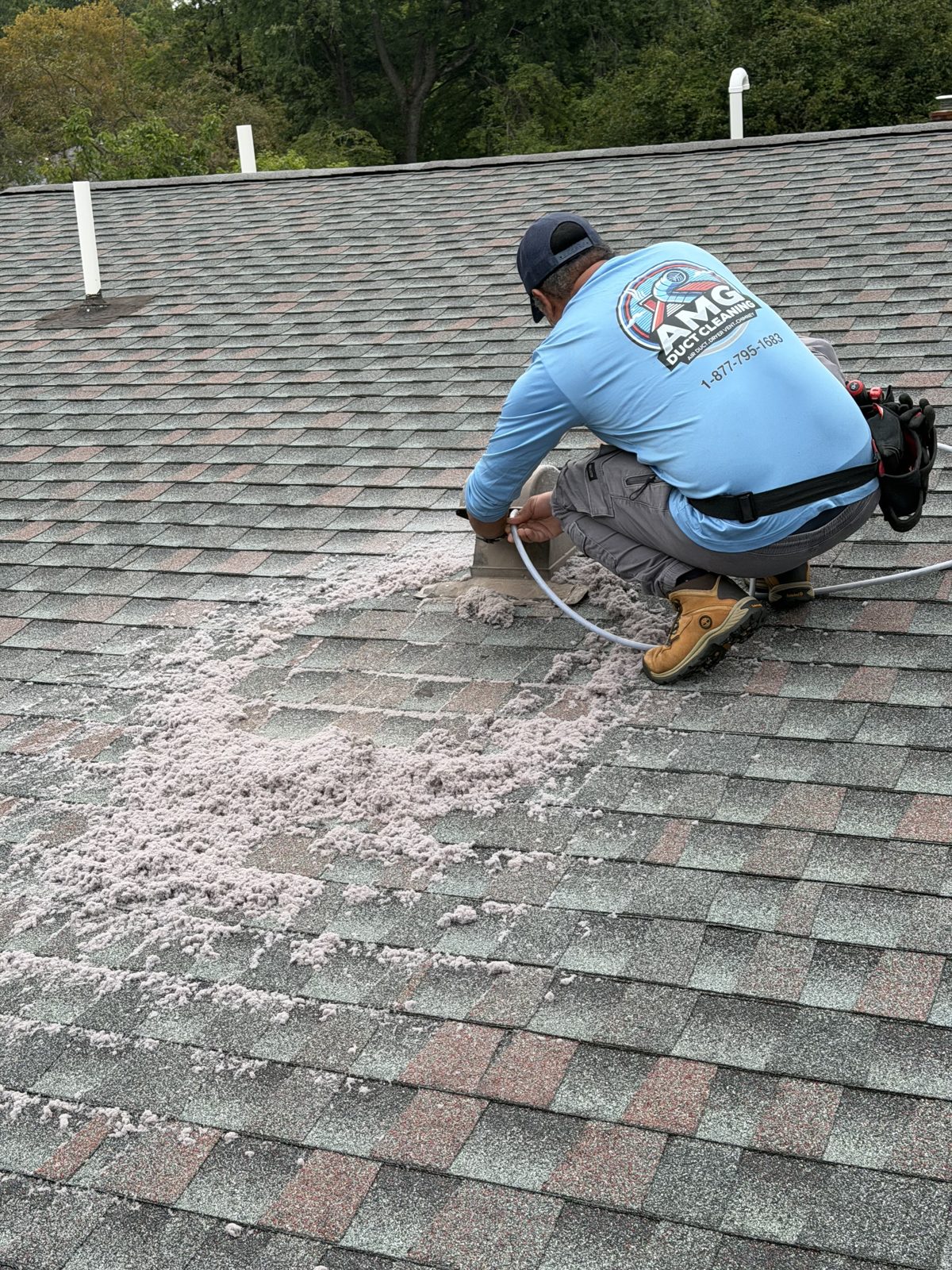 An AMG technician cleaning a vent on a roof