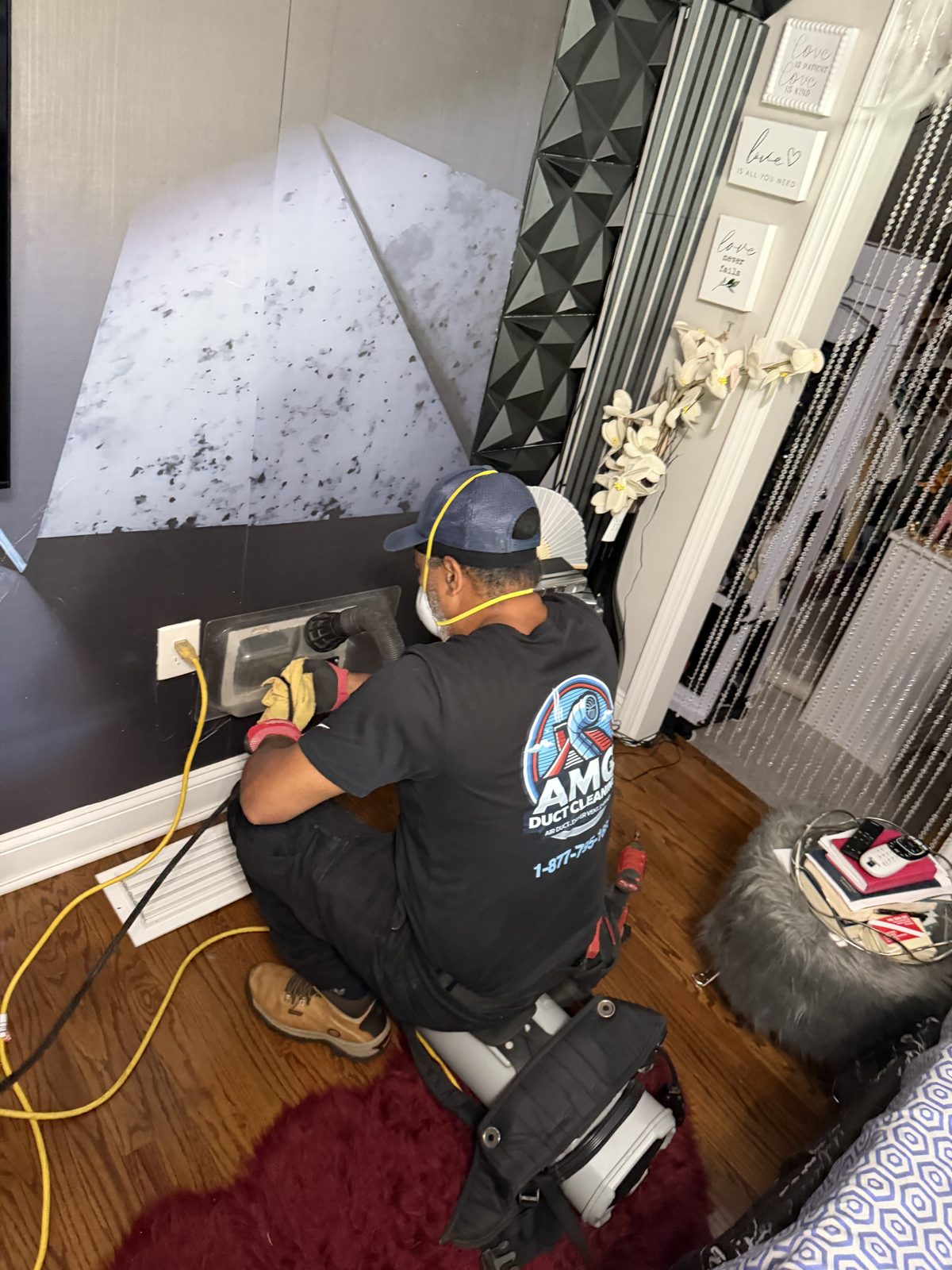 An AMG technician servicing a duct inside a home